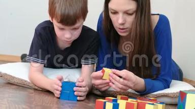 妈妈和儿子一起玩木制彩色教育玩具<strong>积木</strong>躺在地板上。 他们建造了一个蓝色的<strong>盒子</strong>。